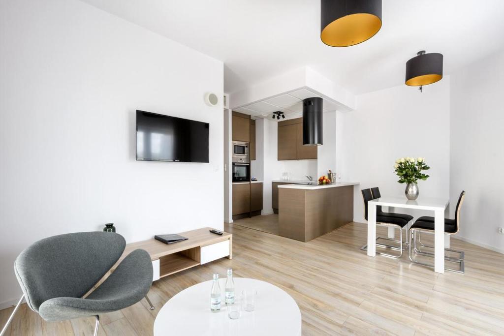 Il comprend un salon avec une table et des chaises ainsi qu'une cuisine. dans l'établissement Apartment & Rooms at Wierzbiecice street, à Poznań