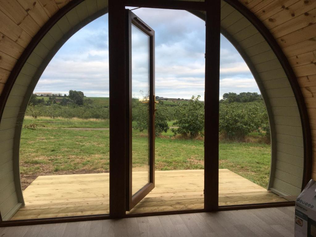 an arched window with a view of a field at Orchard Luxe Glamping Pod in Dungannon