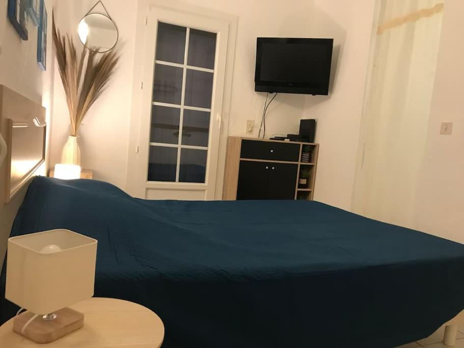 - une chambre avec un lit bleu et une télévision dans l'établissement La Petite Mer’veille, à Sainte-Maxime