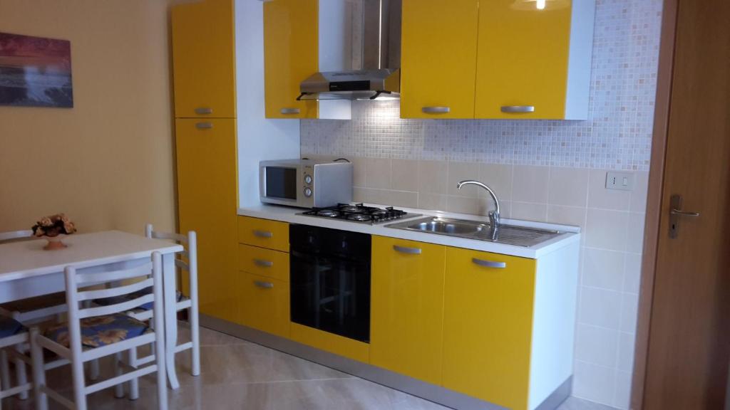トラーパニにあるCasa di Tonyのキッチン(黄色のキャビネット、シンク、テーブル付)