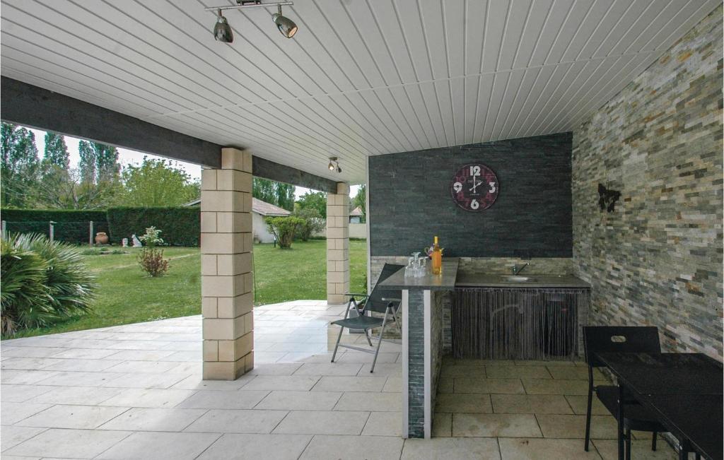 a patio with a table and a clock on the wall at Stunning Home In Saint-vivien-de-medoc With 4 Bedrooms And Outdoor Swimming Pool in Saint-Vivien-de-Médoc
