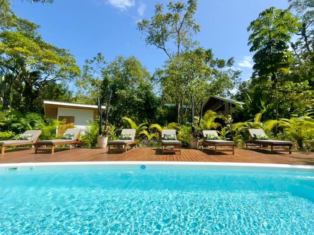 uma piscina em frente a uma casa com árvores em Dragonfly Beach Retreat Beachfront Casitas-Adult Only em Punta Uva