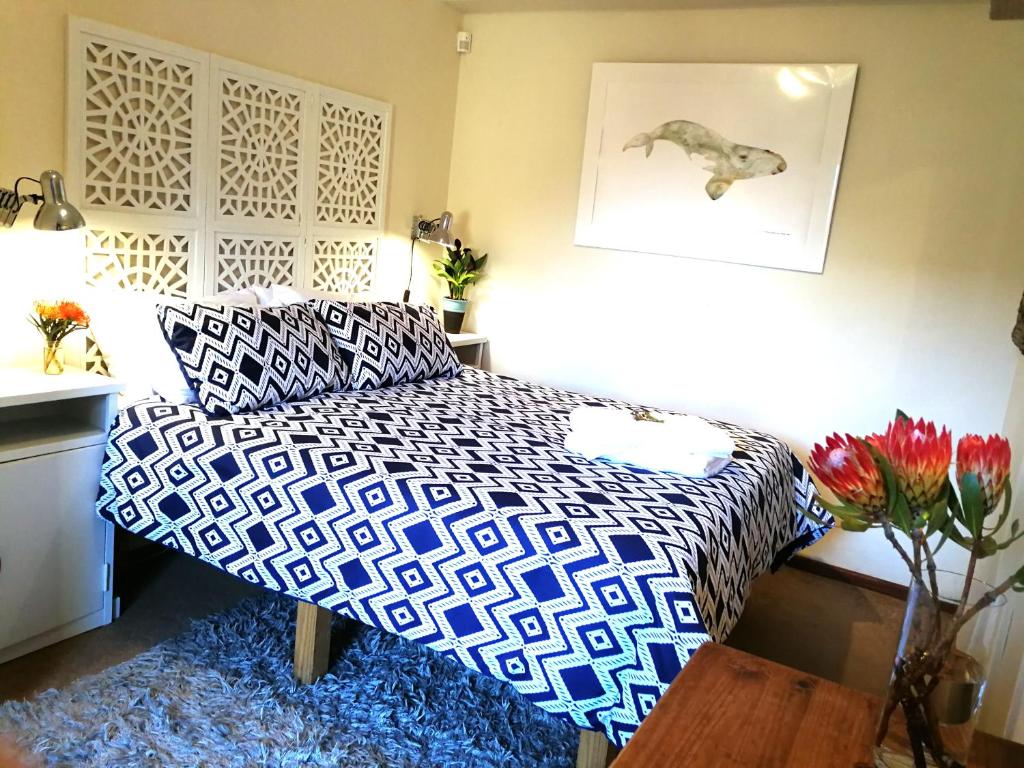 a bedroom with a bed and a vase of flowers at Cottage in Voëlklip between mountain and sea in Hermanus