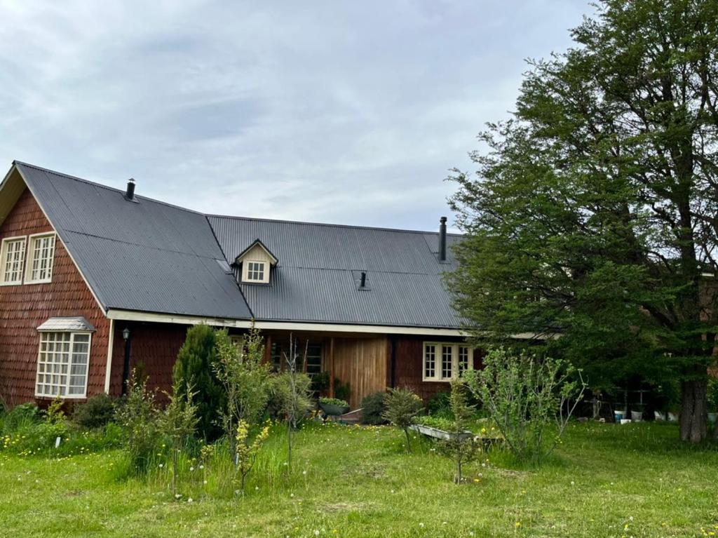 ein rotes Backsteinhaus mit schwarzem Dach in der Unterkunft Hospedaje BoppHouse in Coihaique