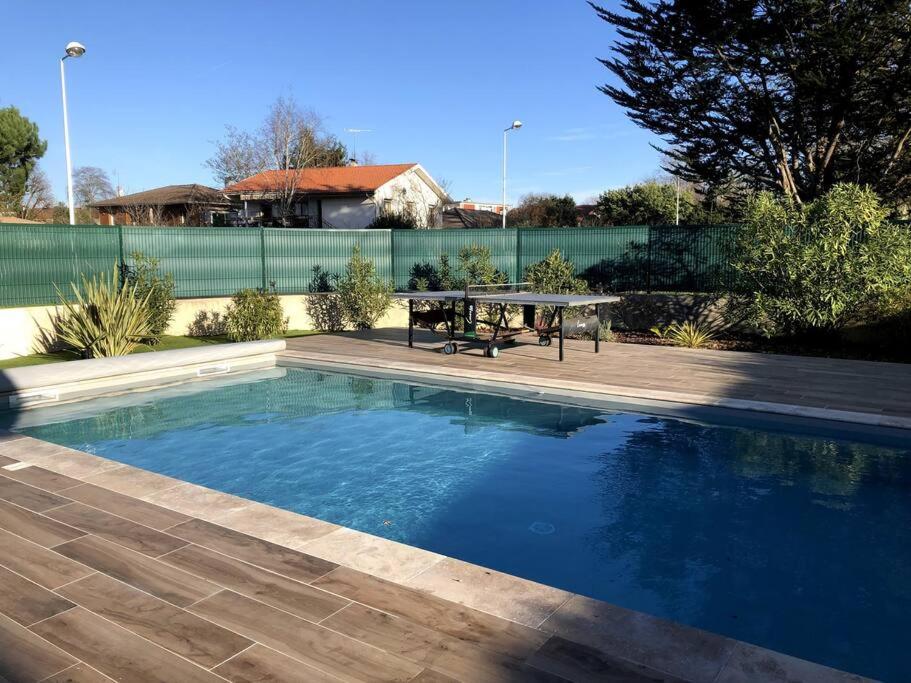 - une piscine avec une table de pique-nique à côté d'une clôture dans l'établissement Belle maison familiale / grande piscine chauffée, à Biscarrosse