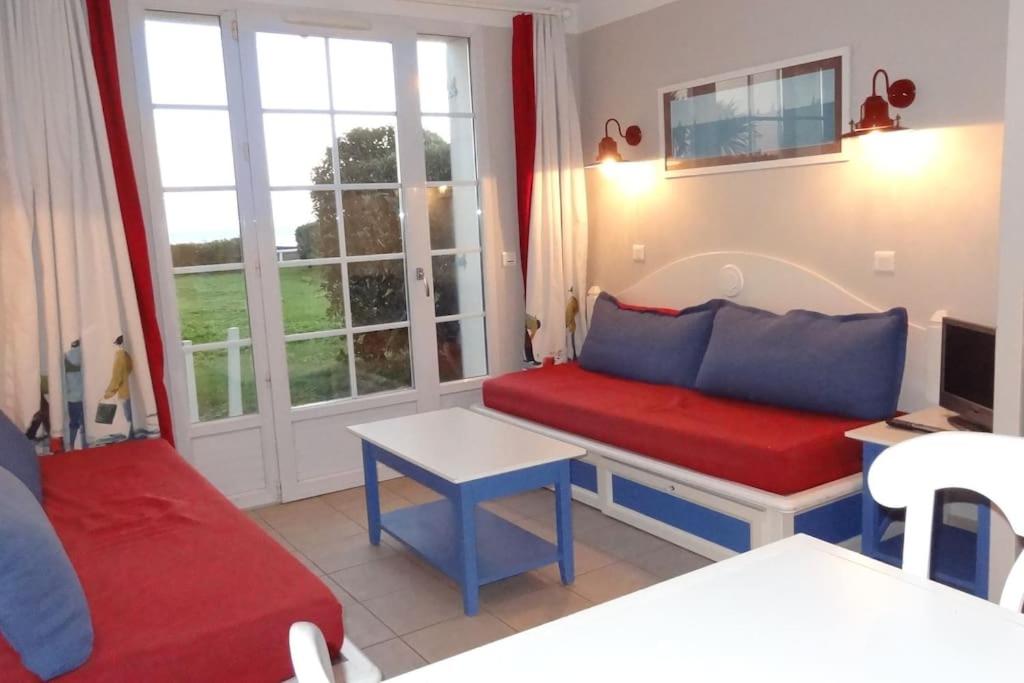 ein Wohnzimmer mit einem roten und blauen Sofa und einem Fenster in der Unterkunft ArMen in Le Guilvinec