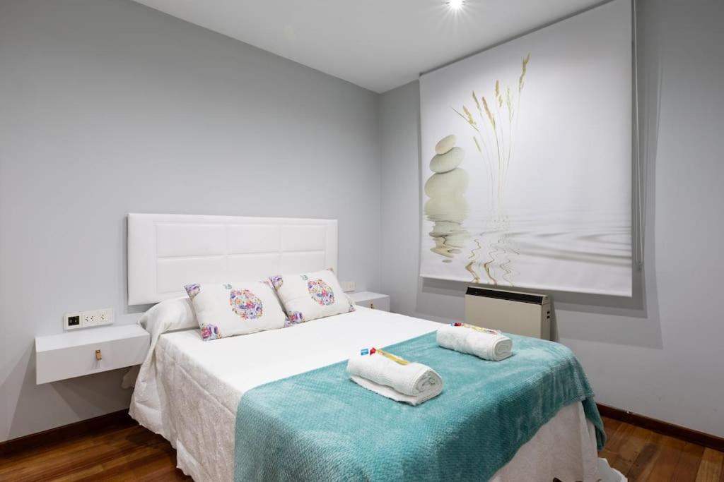 a white bedroom with a bed with towels on it at PISO MODERNO COMPLETO LOVE MARIN 2 in Marín