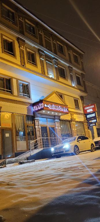 um carro estacionado em frente a um edifício à noite em Güngören Hotel em Kars