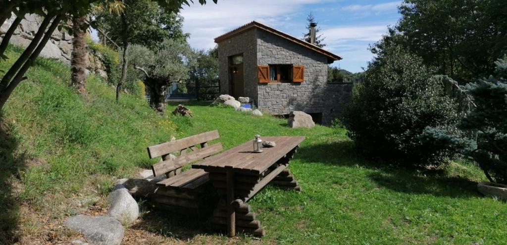a wooden bench sitting in the grass next to a building at Els Pins d'Abella in Camprodon