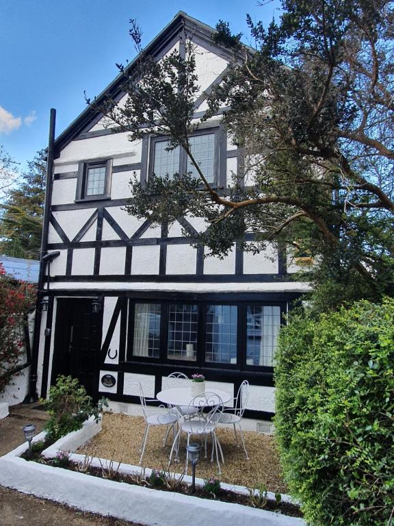 a white and black house with a table and chairs at Bournemouth secluded cottage 10mins walk to beach in Bournemouth