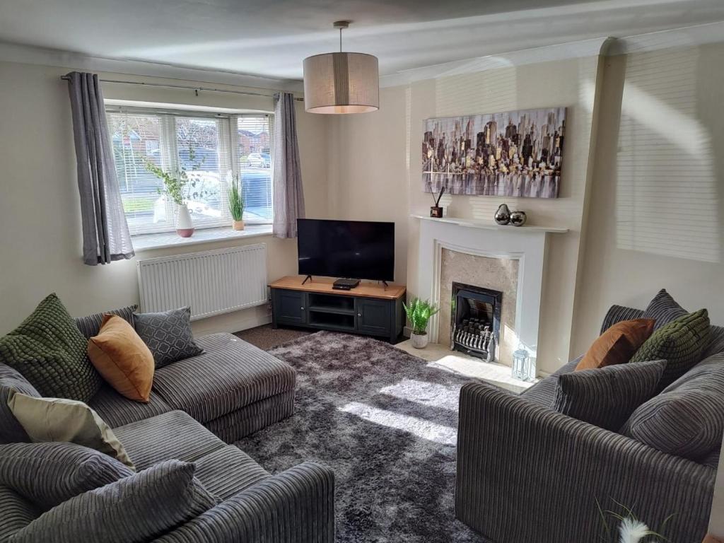 sala de estar con 2 sofás y chimenea en Wentworth Drive Contractor and family 3 bed Home Grantham en Lincolnshire
