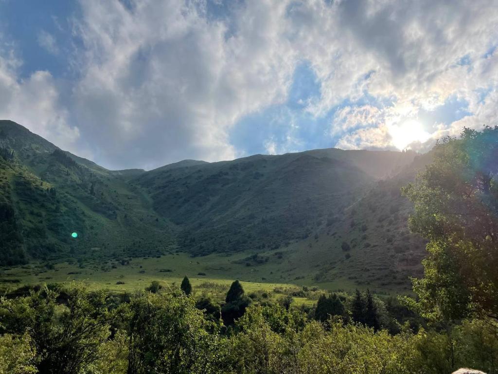 a view of a mountain valley with the sun shining on it at Гостевой дом Темирлан in Kegeti