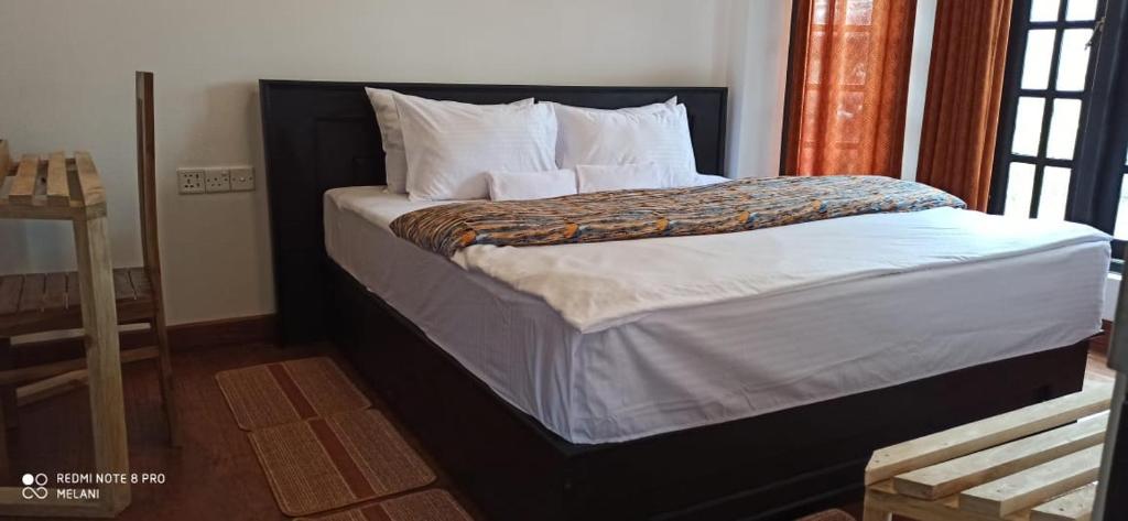 1 dormitorio con 1 cama grande con sábanas y almohadas blancas en Heart of the Hill en Nuwara Eliya