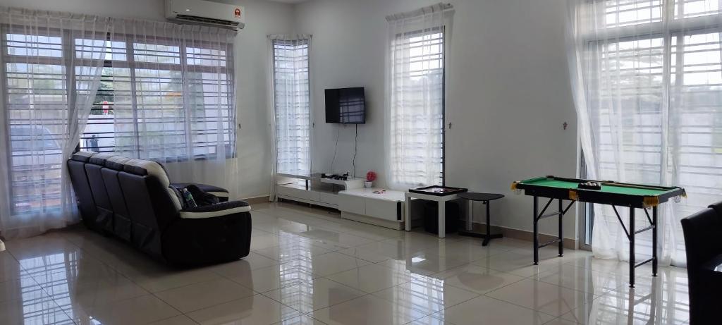 a living room with a couch and a ping pong table at HK68 Desaru homestay in Kangkar Chemaran