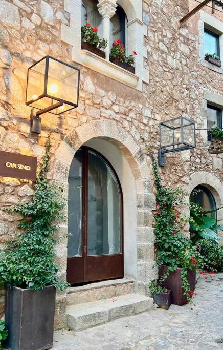 a stone building with a door and two plants at Can Senio 1 in Tossa de Mar
