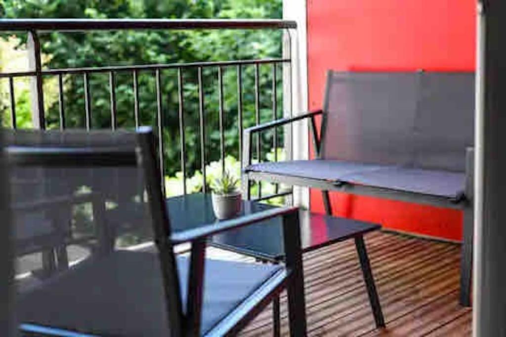 une terrasse couverte avec un banc et une table sur un balcon dans l'établissement Patio Arena, à Bayonne