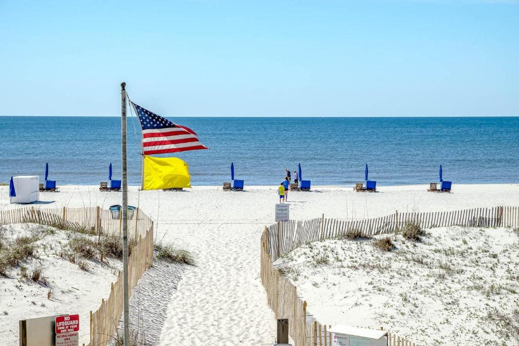 an american flag on a sandy beach with the ocean at Island Winds East by Brett Robinson Vacations in Gulf Shores
