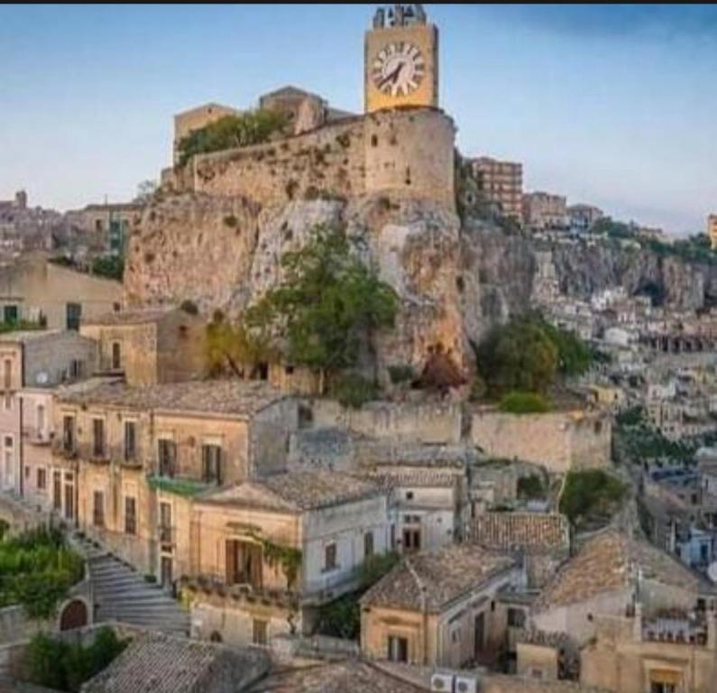 a clock tower on top of a mountain with houses at Casa vacanze Modica Charme in Modica