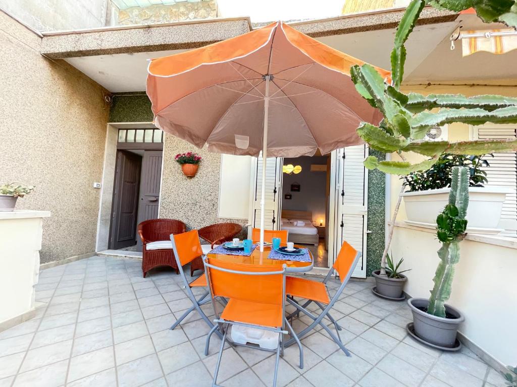 einen Tisch und Stühle mit Sonnenschirm auf einer Terrasse in der Unterkunft Casa Palma a 100 passi dal mare in Marina di Ragusa