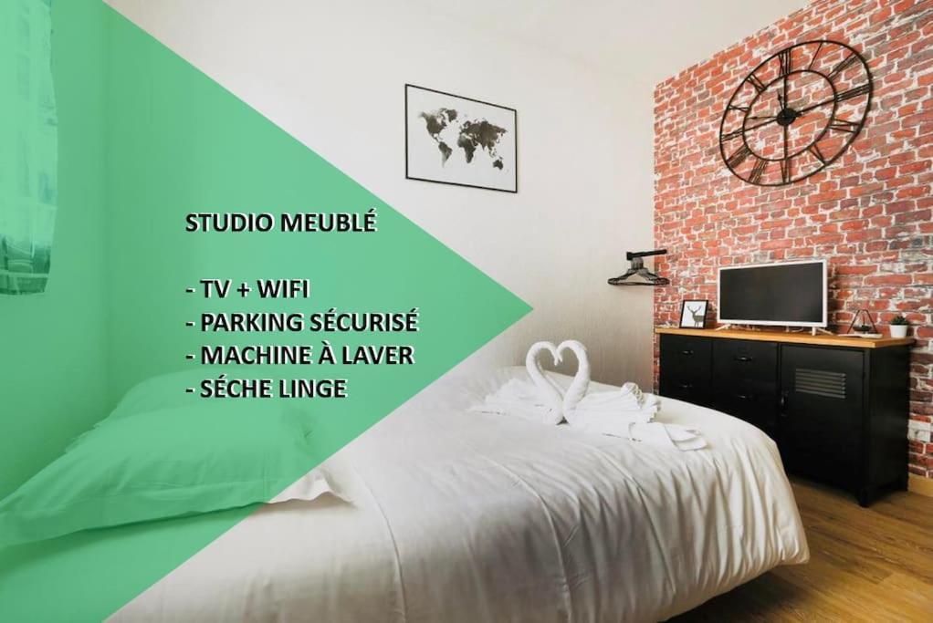 1 dormitorio con 1 cama y reloj en una pared de ladrillo en Studio proche Tours avec wifi en Chambray-lès-Tours