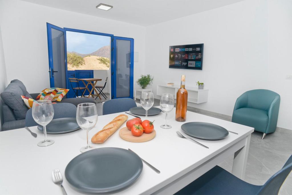 Un comedor con una mesa con platos y copas de vino. en Apartamento Dunas De Famara, en Famara