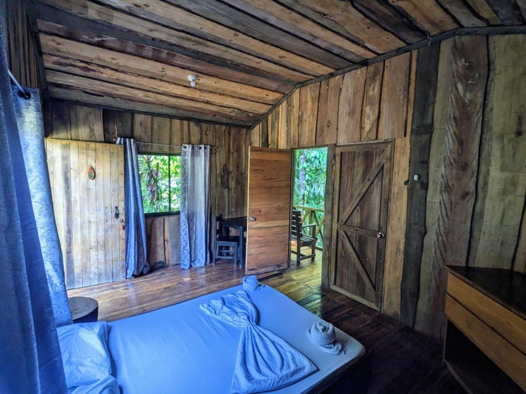1 dormitorio con 1 cama y pared de madera en Citronela Lodge Corcovado en Drake