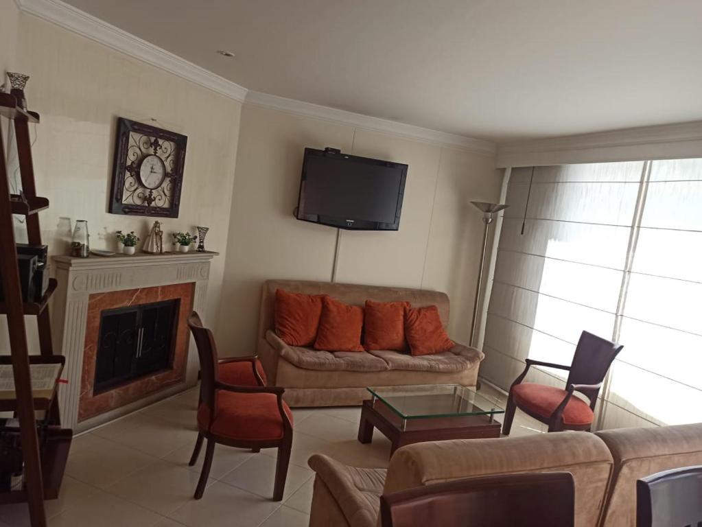 Acogedor apartamento en norte - 2 habitaciones في بوغوتا: غرفة معيشة مع أريكة ومدفأة