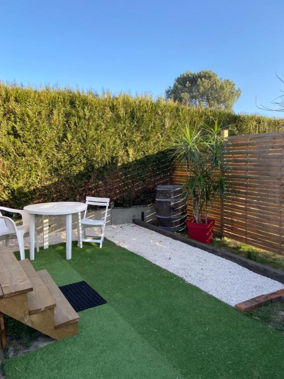 a small backyard with a table and chairs and grass at Gîte Lauraët in Linxe