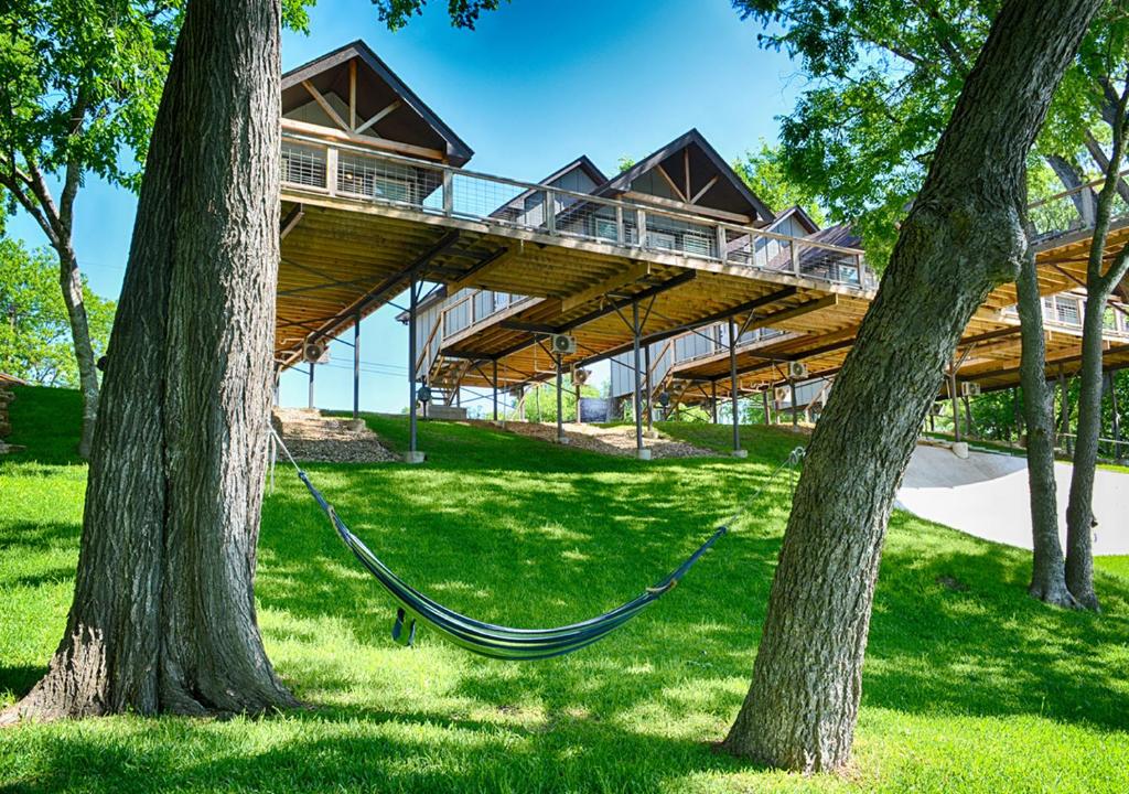 a house with a hammock hanging between two trees at Treetop River Cabins on the Guadalupe River in Center Point