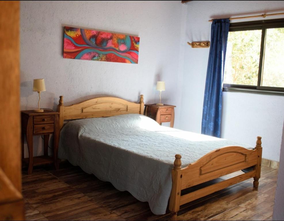 1 dormitorio con cama de madera y ventana en Casa Luz y Armonía en Villa Las Rosas