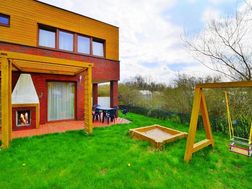 una casa con un patio trasero con un columpio y una mesa en Comfortable holiday home with a nice garden, close to the sea, Sarbinowo, en Sarbinowo