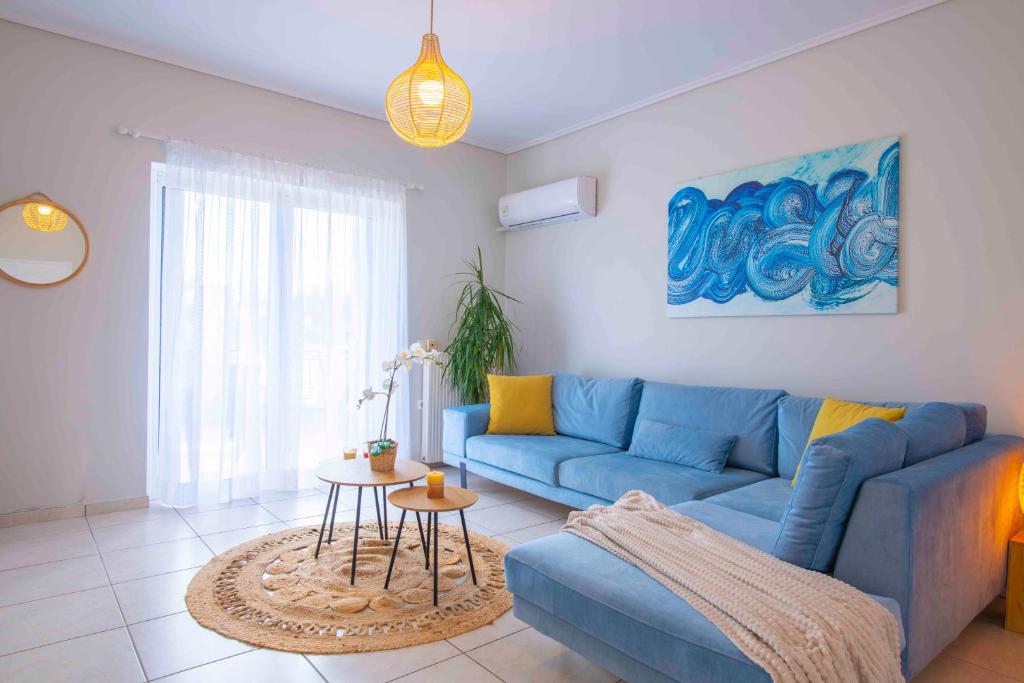 a living room with a blue couch and a table at Kima: Relaxing beach home next to sparkling waters in Nea Makri