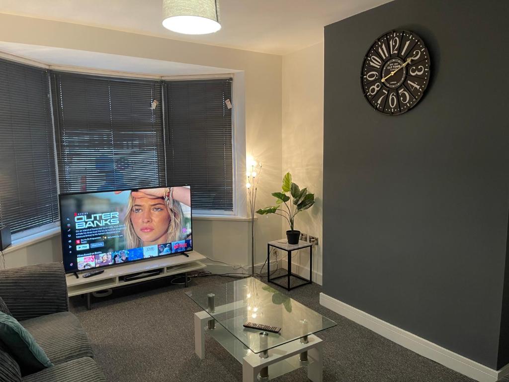 a living room with a tv and a clock on the wall at Campion lodge in Hull