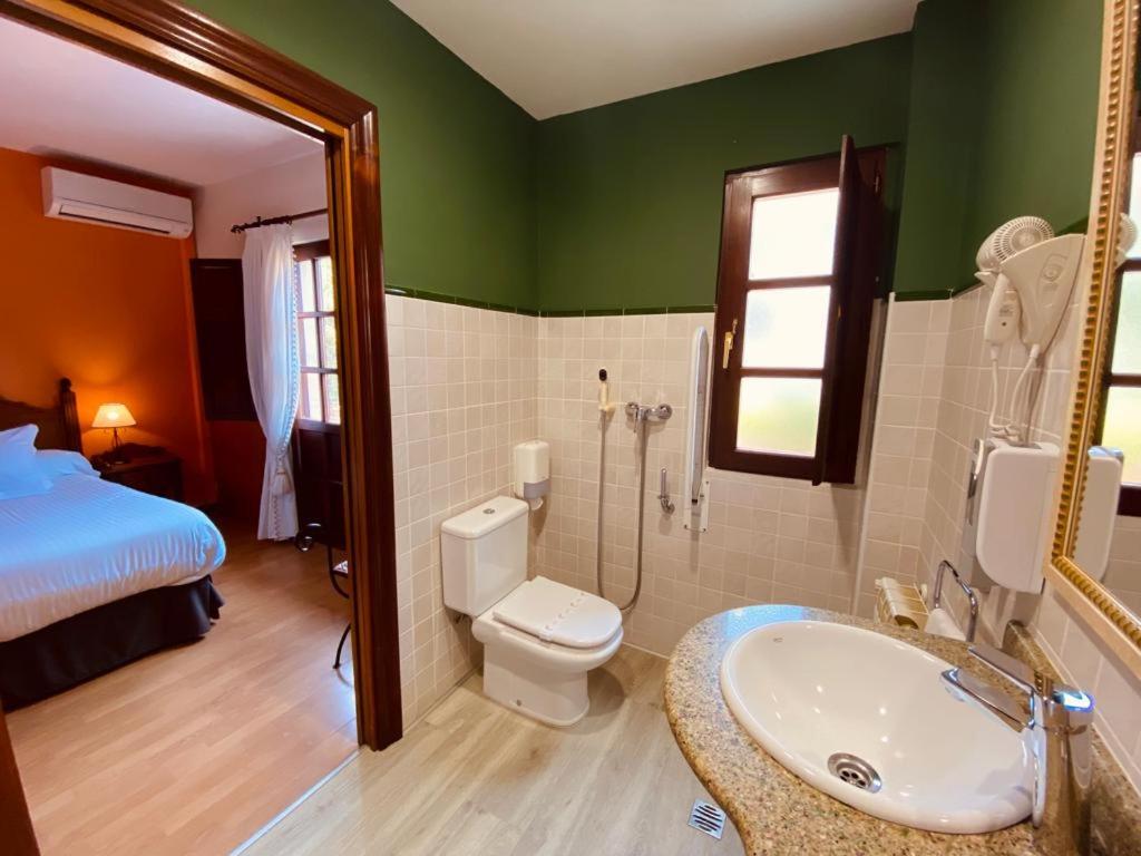 a bathroom with a sink and a toilet and a bed at El Tejo de Comillas in Comillas