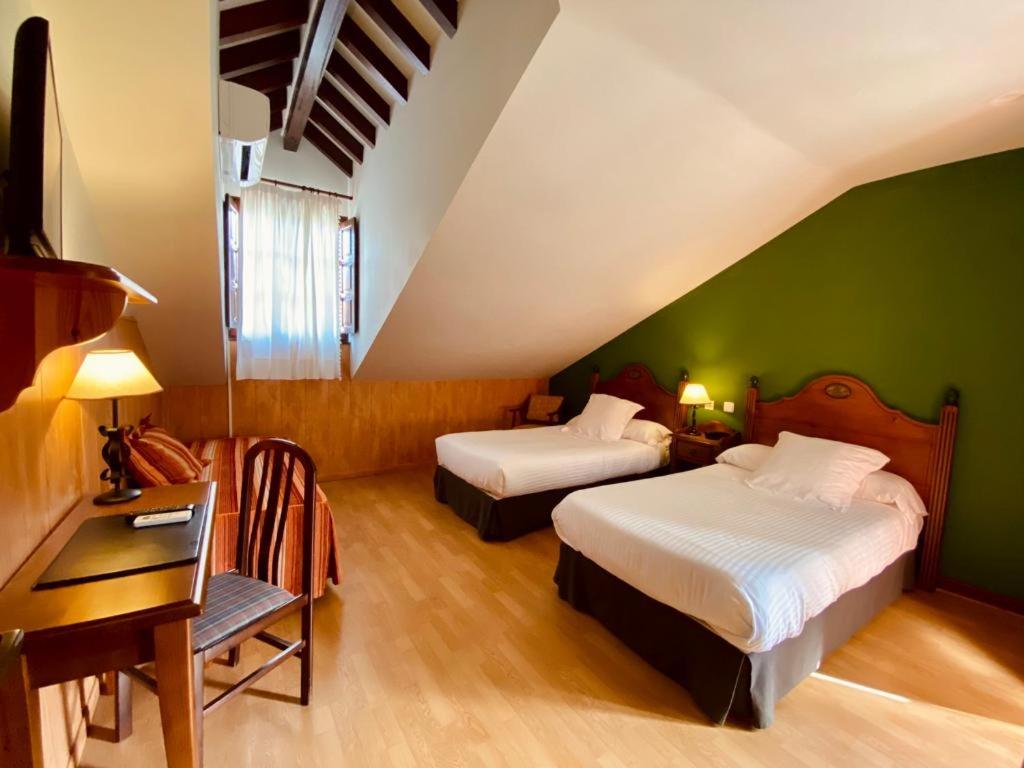 two beds in a room with green walls and a desk at El Tejo de Comillas in Comillas