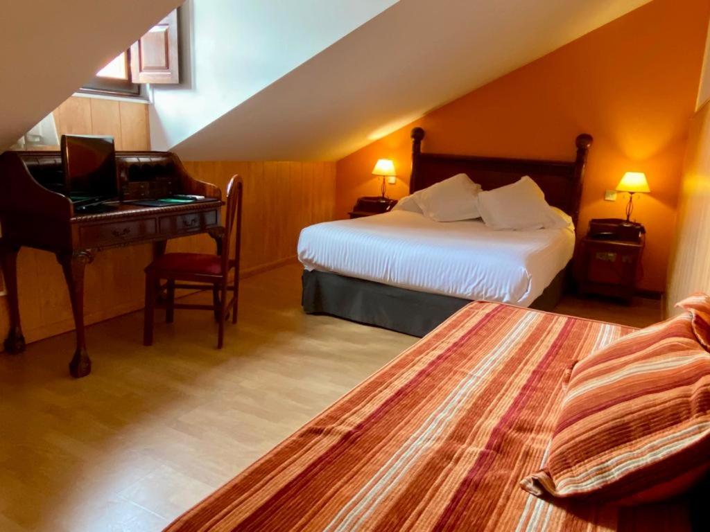 a hotel room with a bed and a desk with a laptop at El Tejo de Comillas in Comillas