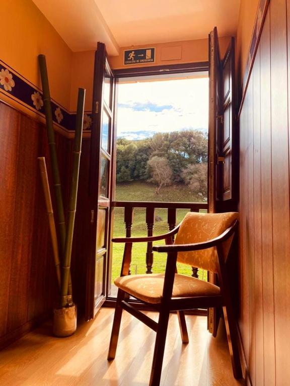 a wooden chair sitting in front of a window at El Tejo de Comillas in Comillas