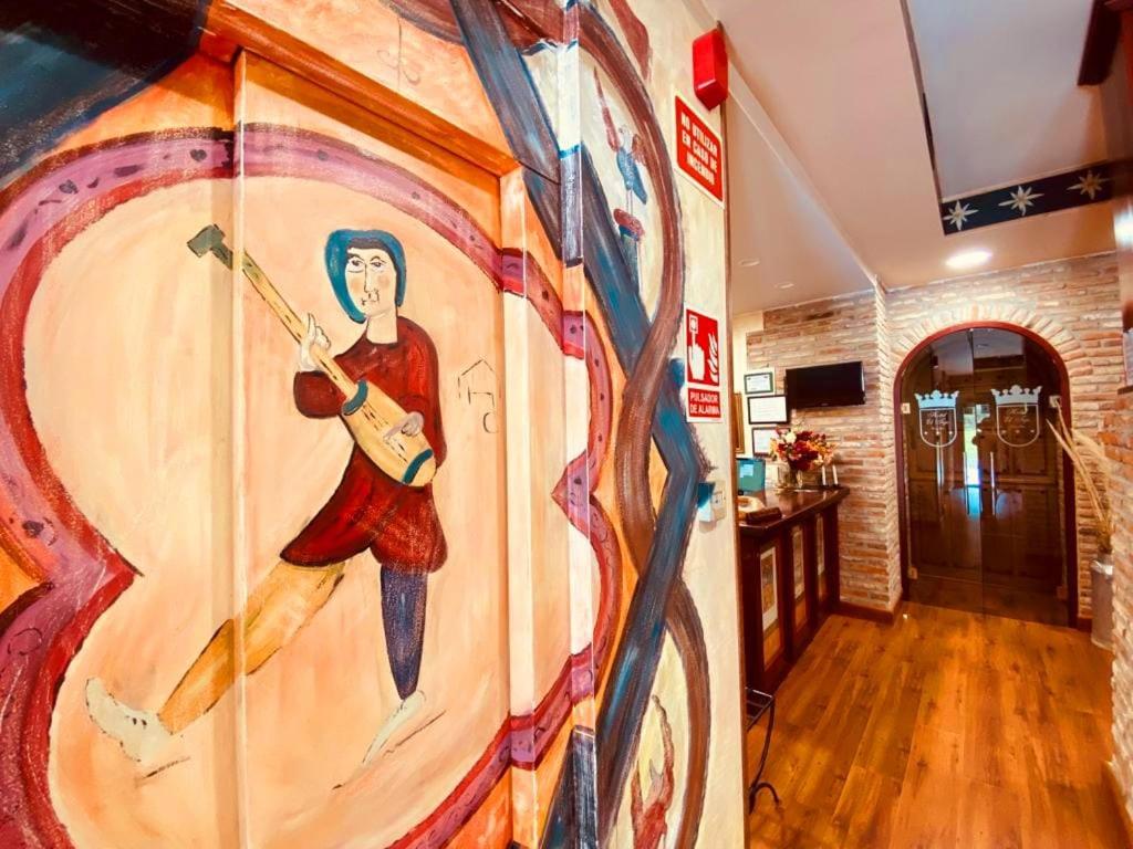 a wall with a painting of a man playing a guitar at El Tejo de Comillas in Comillas