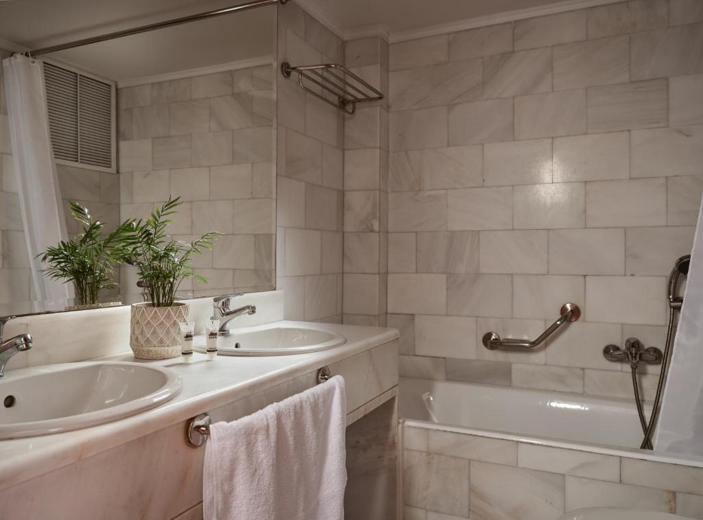 a bathroom with a tub and a sink and a tubermott at Strada Marina Hotel in Zakynthos