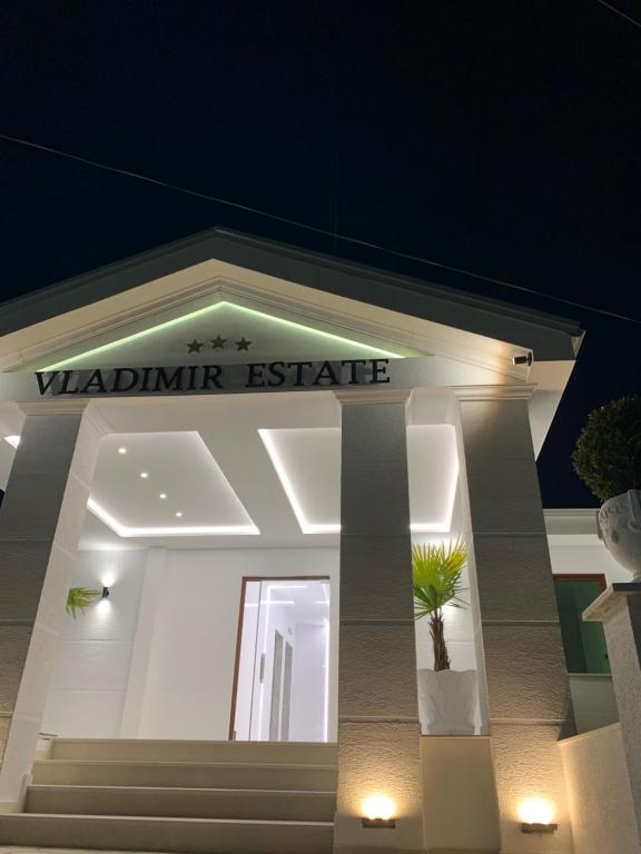 Vladimir Estate Hotel في غيروكاستر: مبنى أبيض مع لافتة تقرأ الجريئة