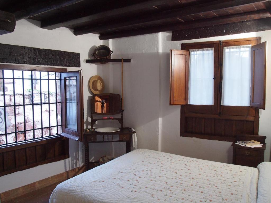 a bedroom with a bed and two windows at Posá la Cestería in Baños de la Encina