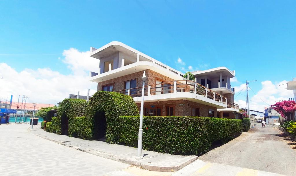 a large house with bushes in front of a street at Hotel StarFish in Puerto Villamil