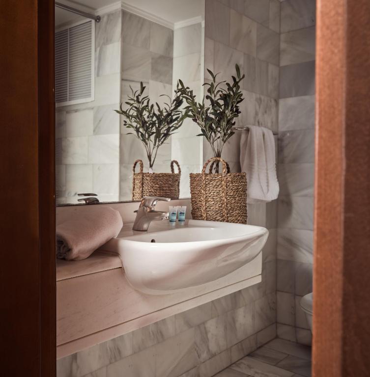 a bathroom with a sink and two potted plants at Strada Marina Hotel in Zakynthos