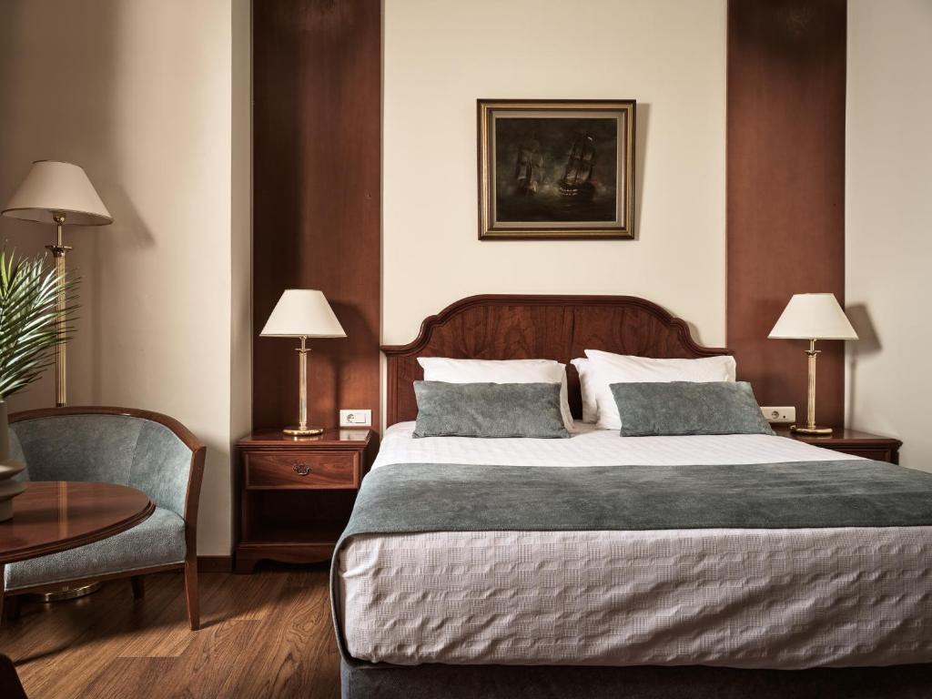 a bedroom with a large bed and a chair at Strada Marina Hotel in Zakynthos
