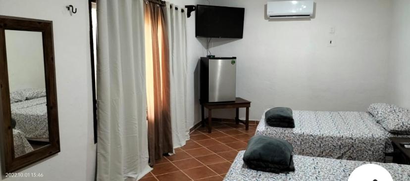 a room with two beds and a mirror and a television at Quinta Calandria Haus in Cancún