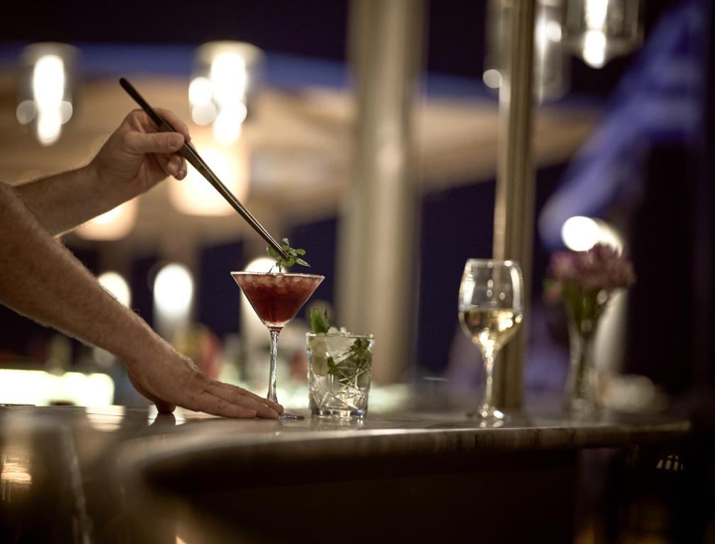 a person is stirring a drink in a martini glass at Strada Marina Hotel in Zakynthos