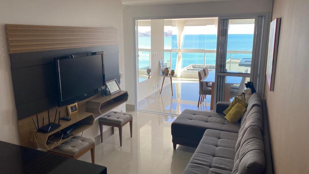 sala de estar con sofá y TV de pantalla plana en AP 3 quartos LUXO a 100 m do mar, en Guarapari