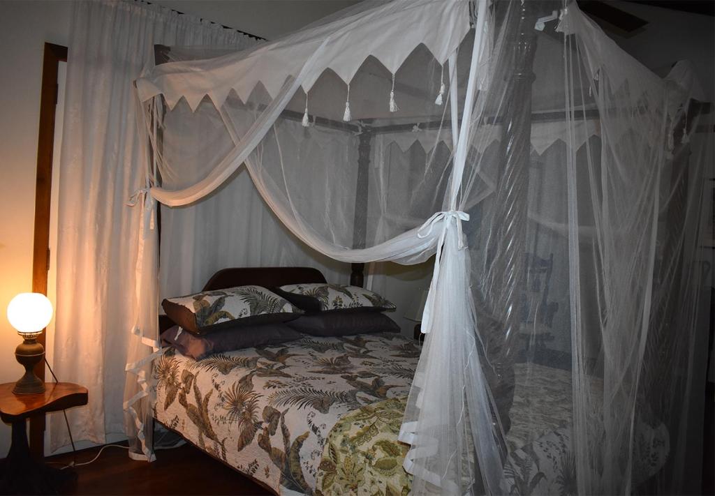 1 dormitorio con cama con dosel y cortinas blancas en Oskar's Rain Forest Retreat, en Nelly Bay