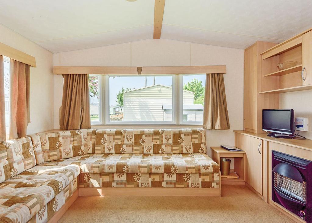 a living room with a couch and a television at Riverside Caravan Park in Bognor Regis
