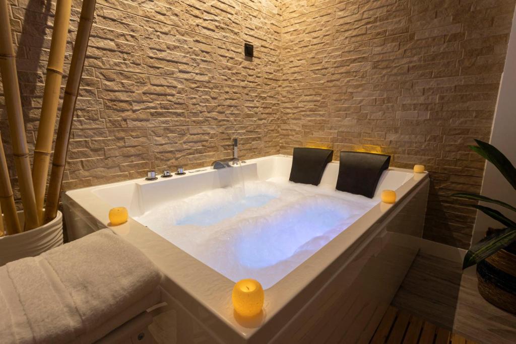 a bathtub in a bathroom with a stone wall at Huellas de la Mancha in Burguillos de Toledo